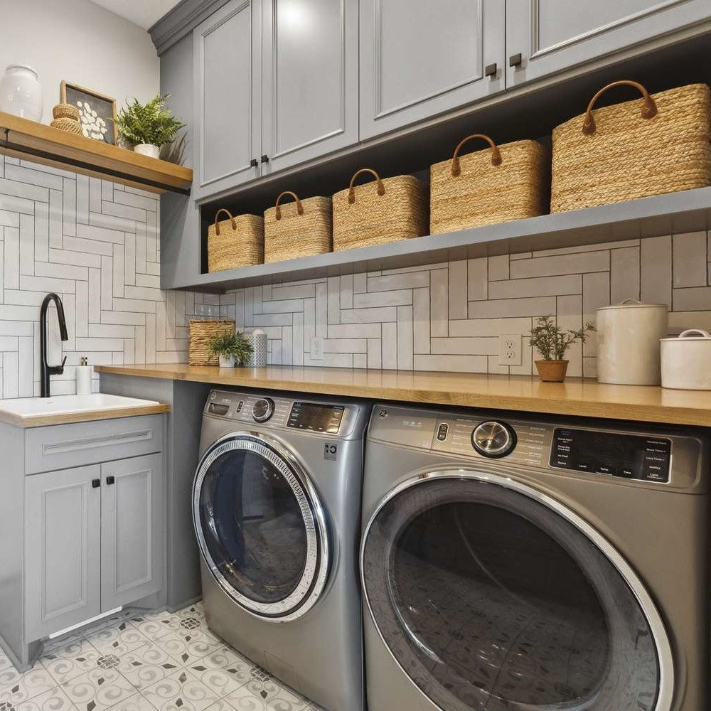 Laundry room with washing machines, wooden counters, and storage baskets.